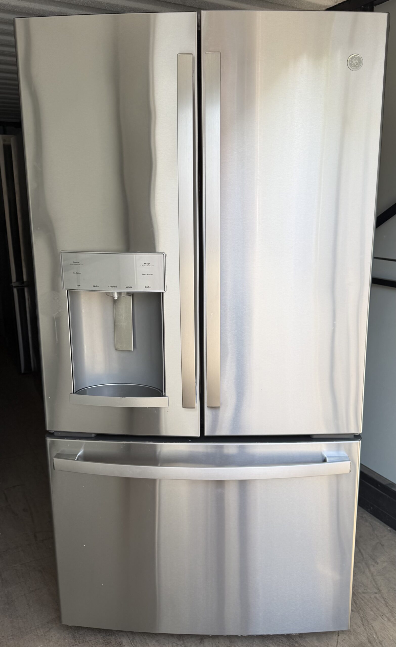 GE 27.7 cu ft French Door Refrigerator in stainless steel with external water and ice dispenser in left door and full-width bottom freezer drawer, front view