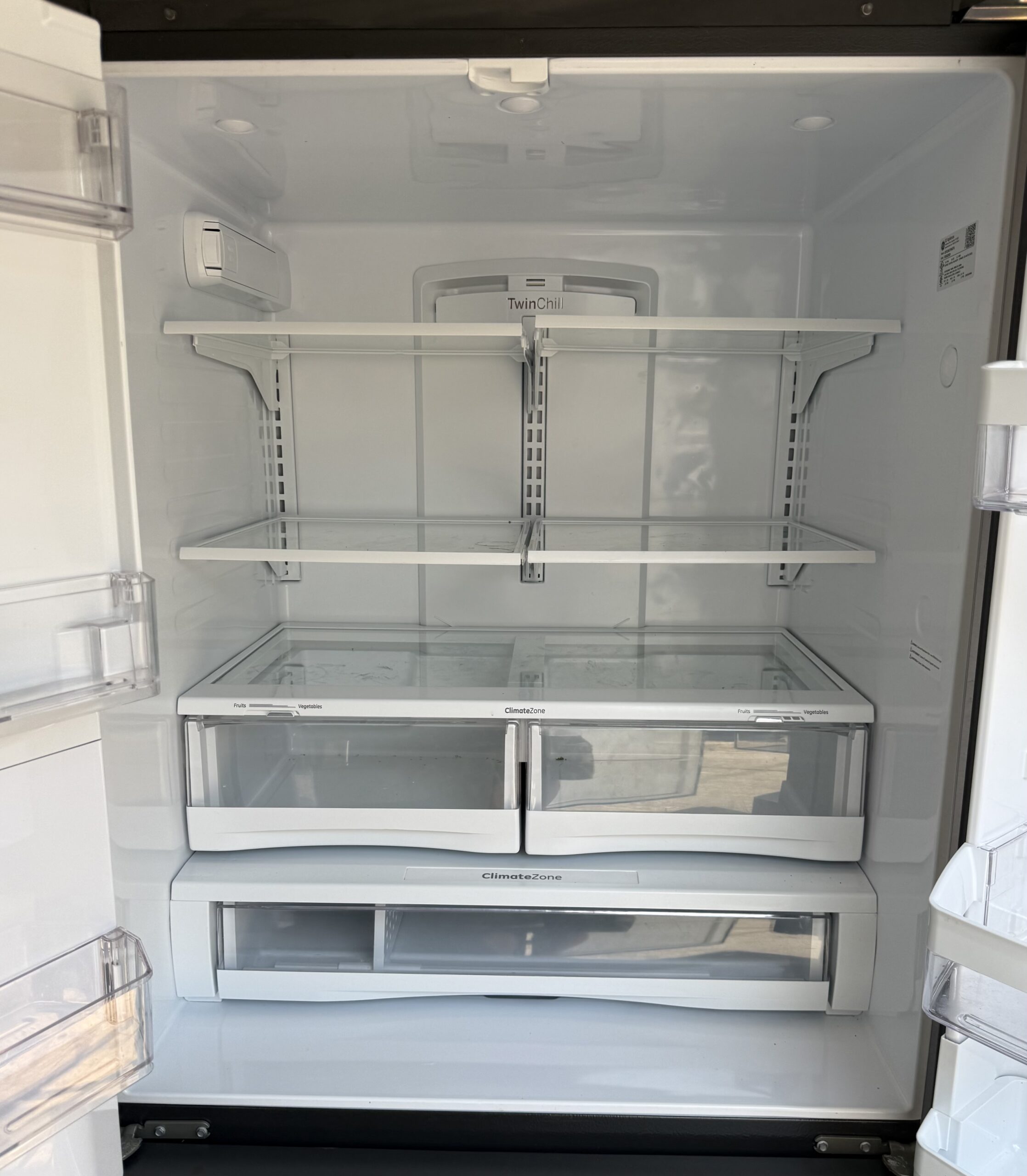 GE French door refrigerator interior showing TwinChill cooling system, ClimateZone produce drawers, and adjustable glass shelves
