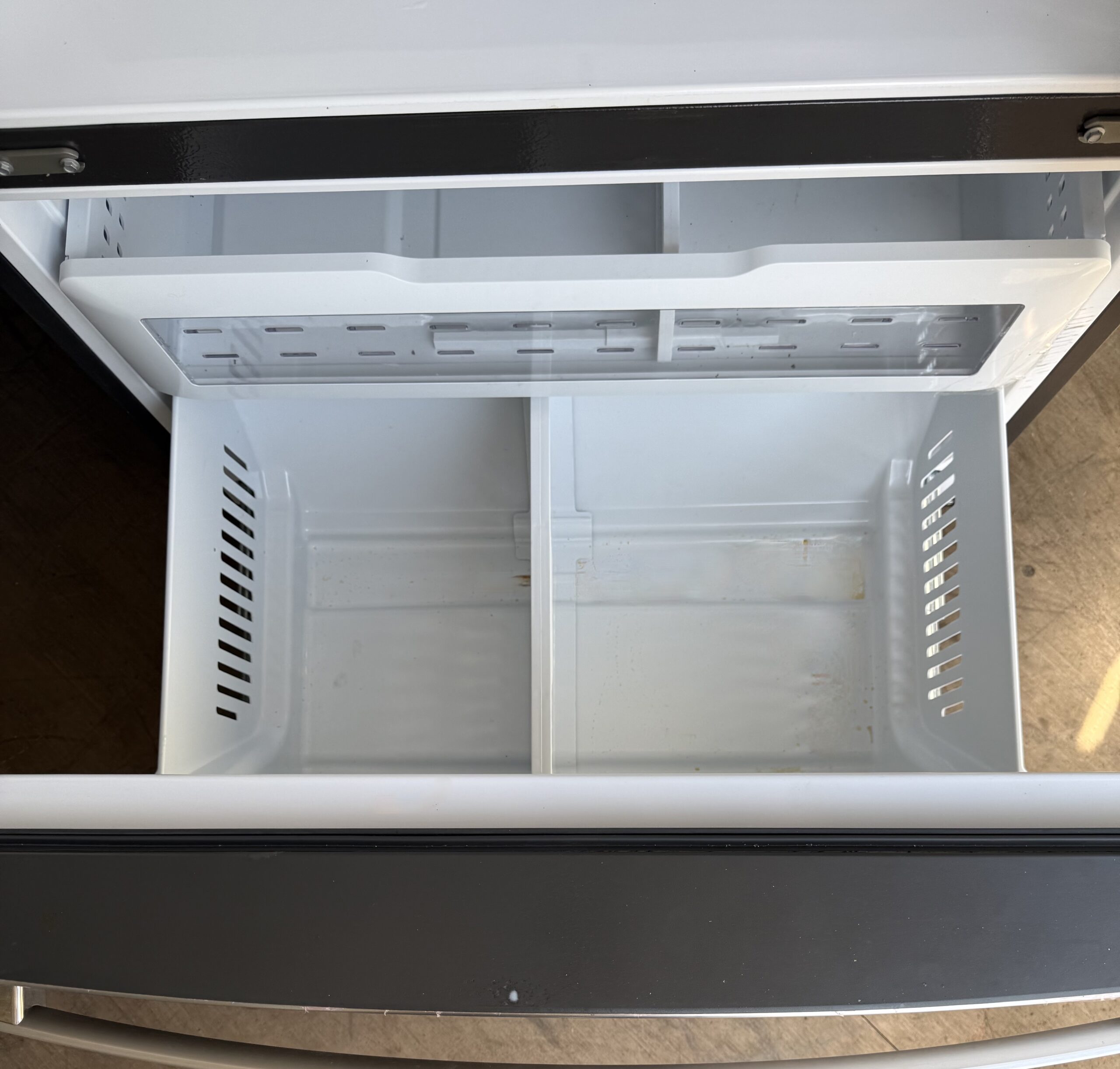 GE refrigerator full-width bottom freezer drawer pulled open showing two-tier organization