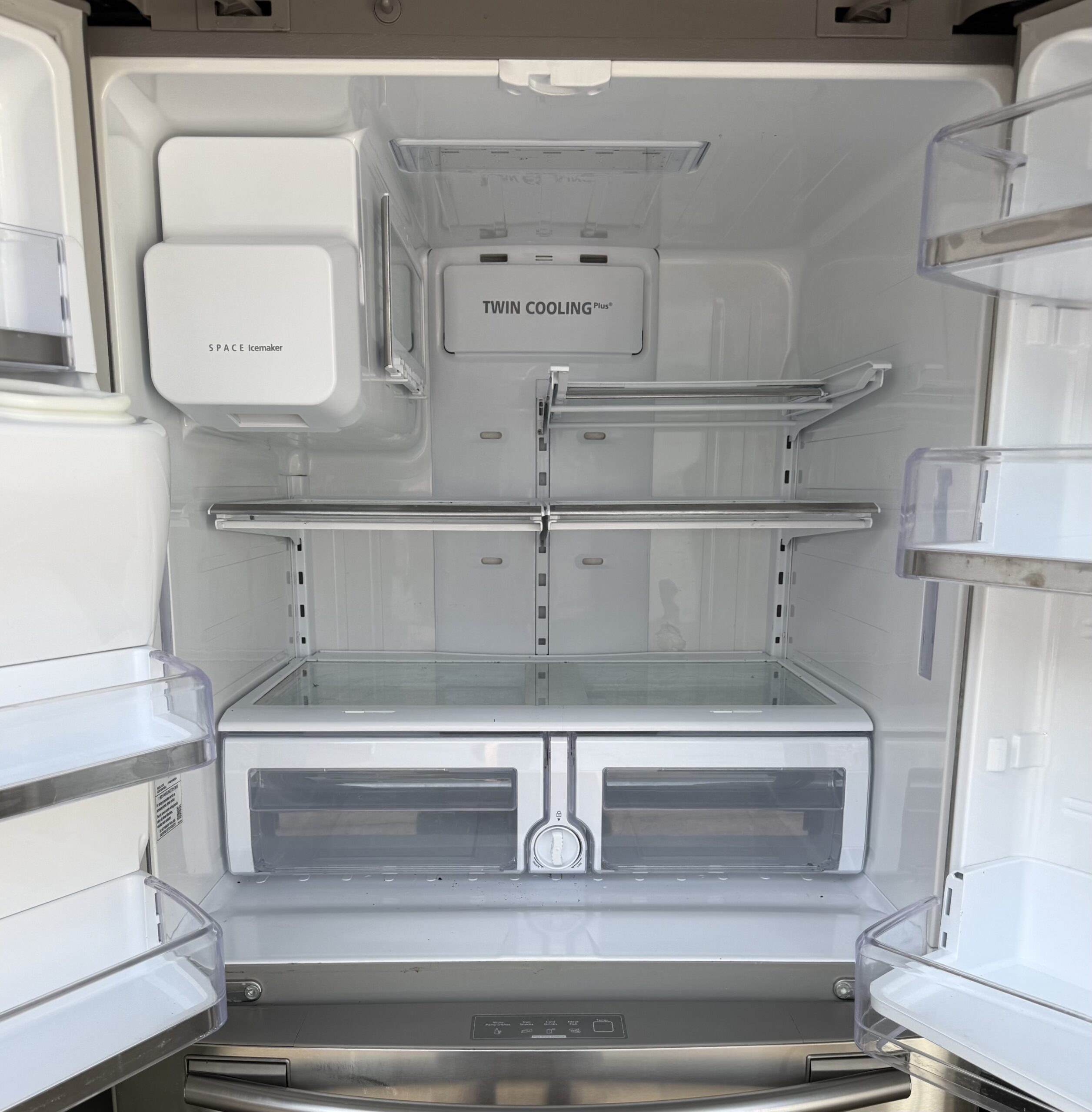 Samsung refrigerator fresh food interior showing Twin Cooling Plus panel, SPACE Icemaker, adjustable glass shelves, and clear produce drawers