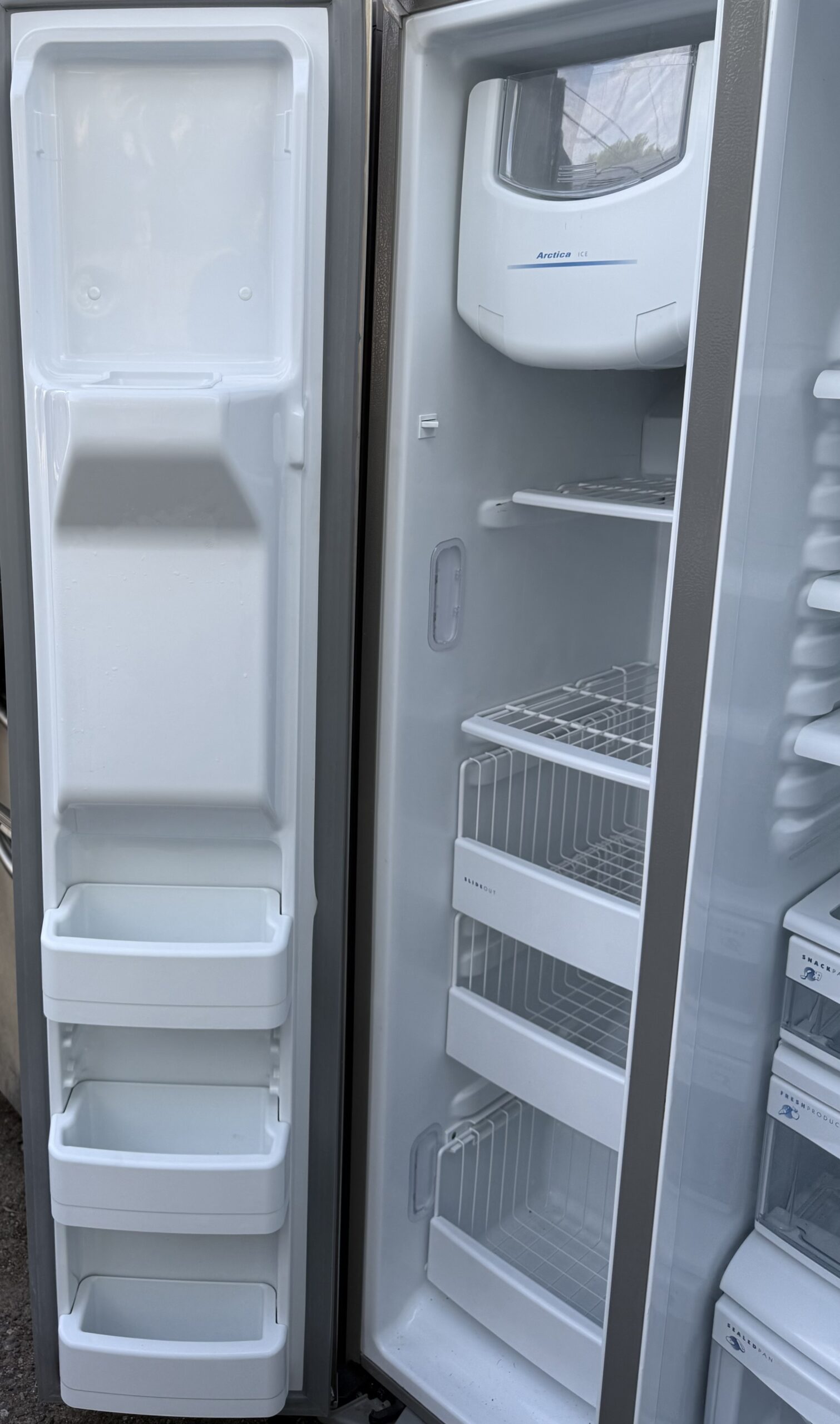 GE Profile refrigerator — freezer side with Arctica ice maker and door storage.