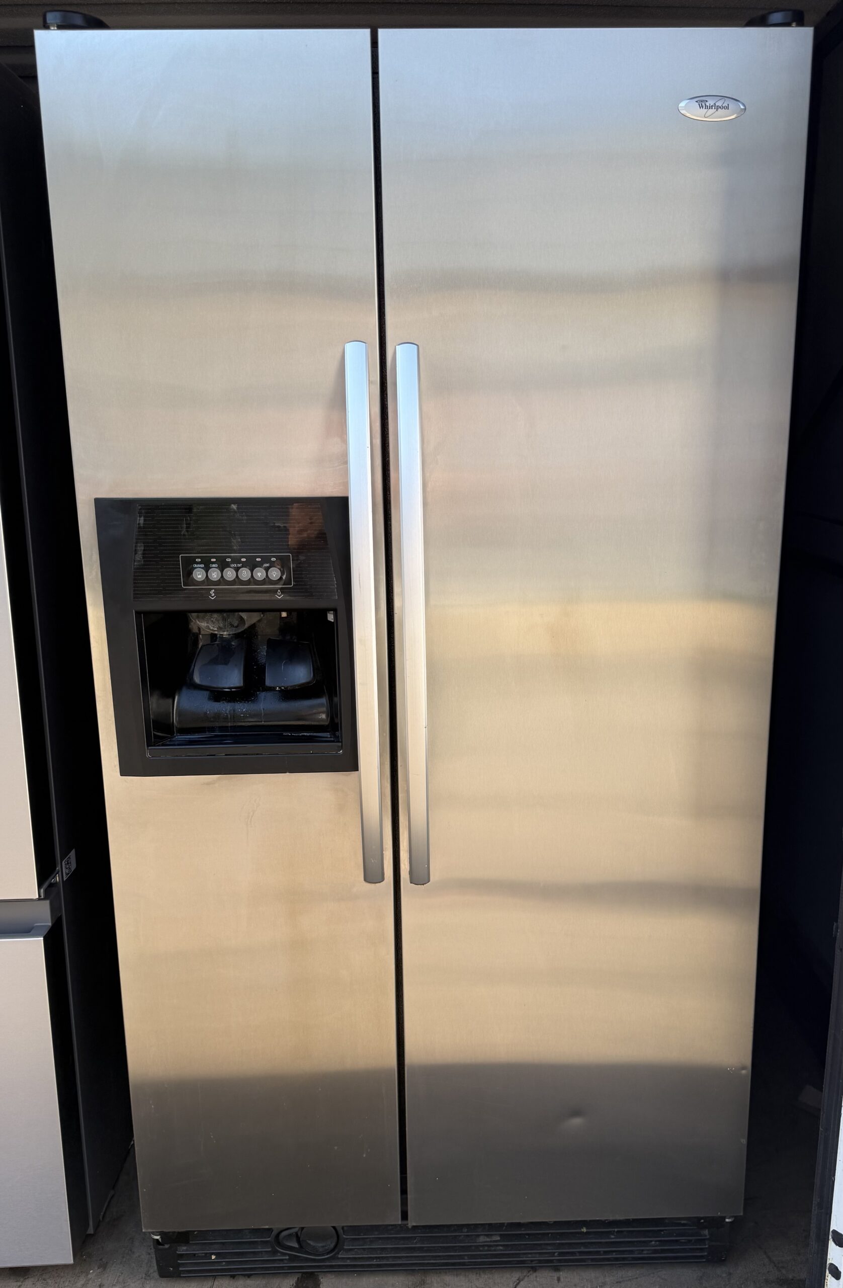 Whirlpool side-by-side refrigerator in stainless steel with ice and water dispenser, front view