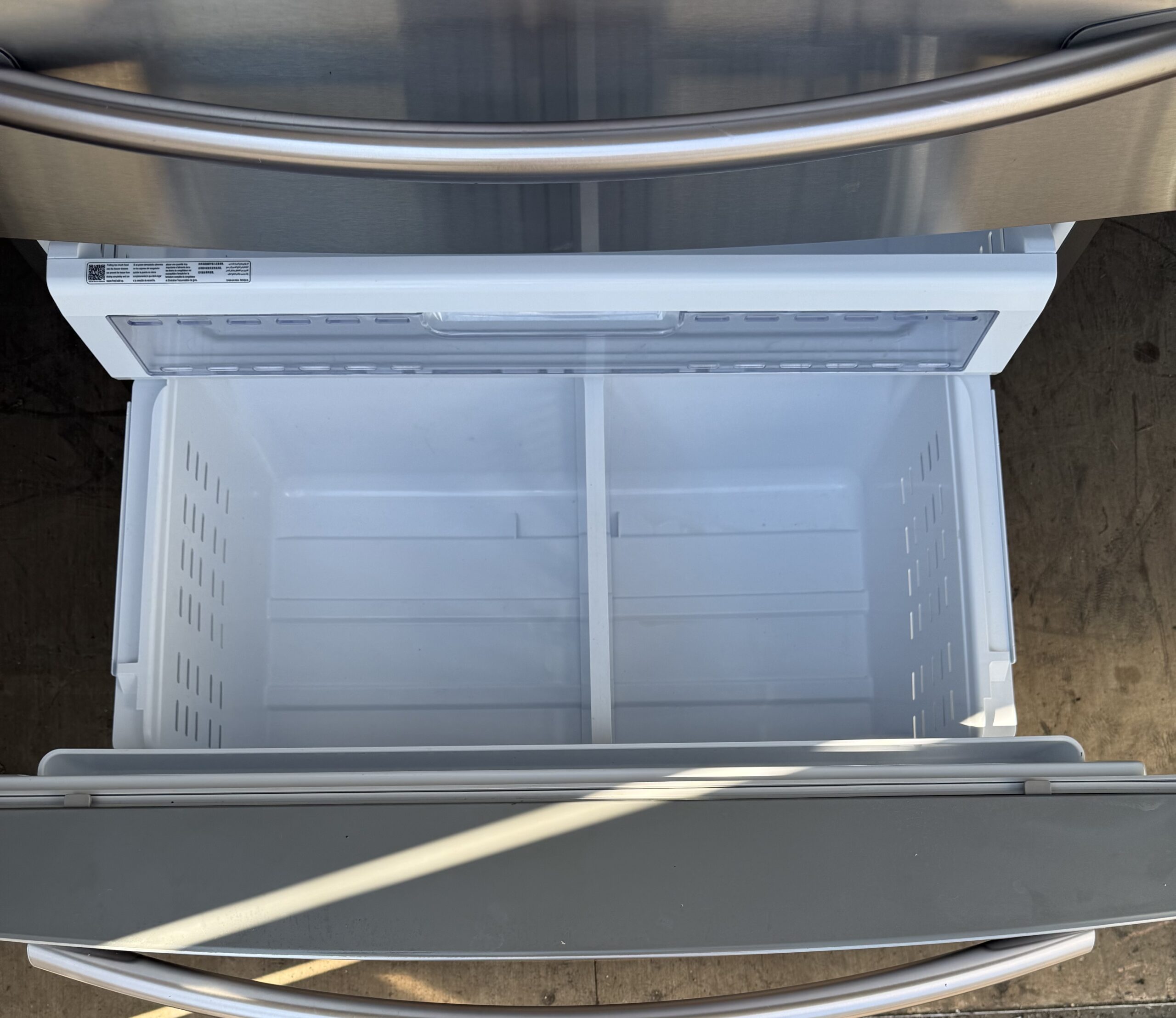 Samsung refrigerator bottom freezer drawer open with divided basket