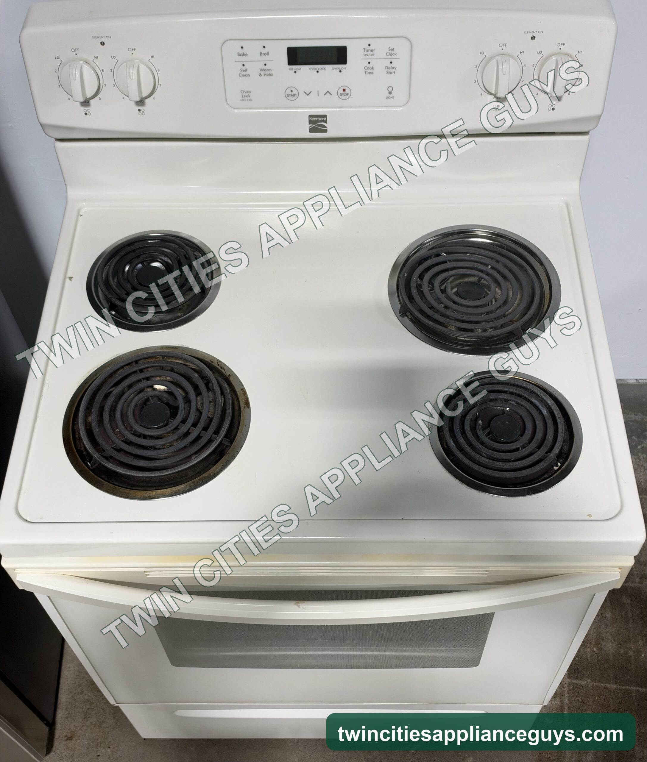 Kenmore electric range coil cooktop seen from above with control knobs and display