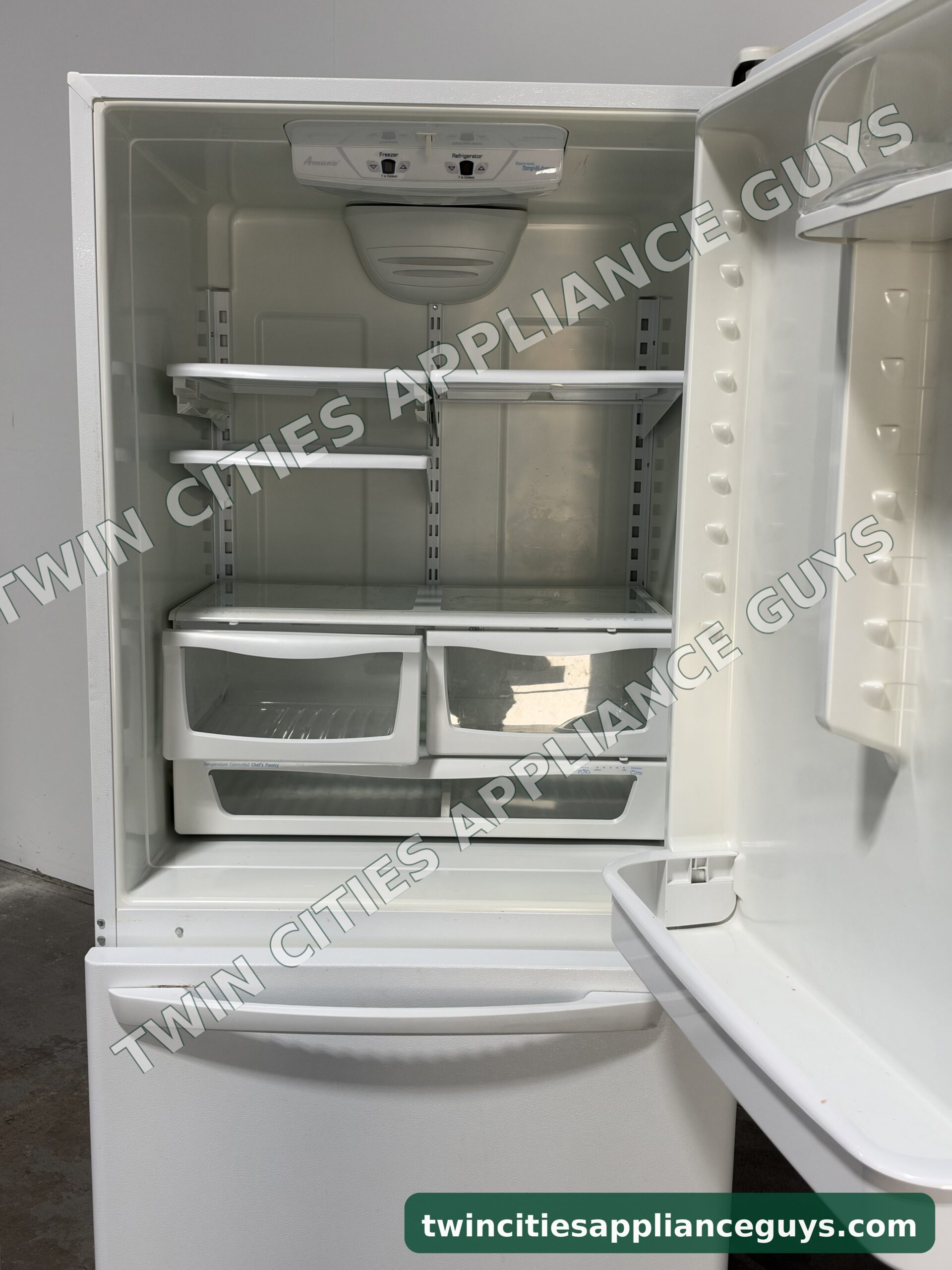 Amana refrigerator door open showing shelves and crisper drawers