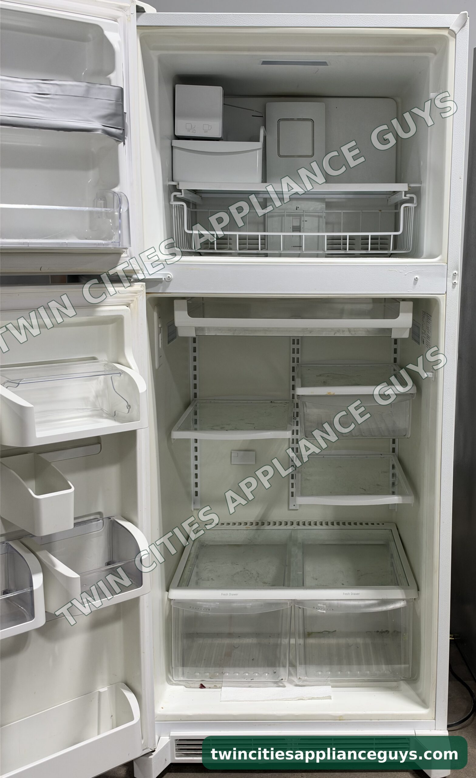 Frigidaire Gallery refrigerator with both doors open showing the ice maker, shelves and crisper drawers