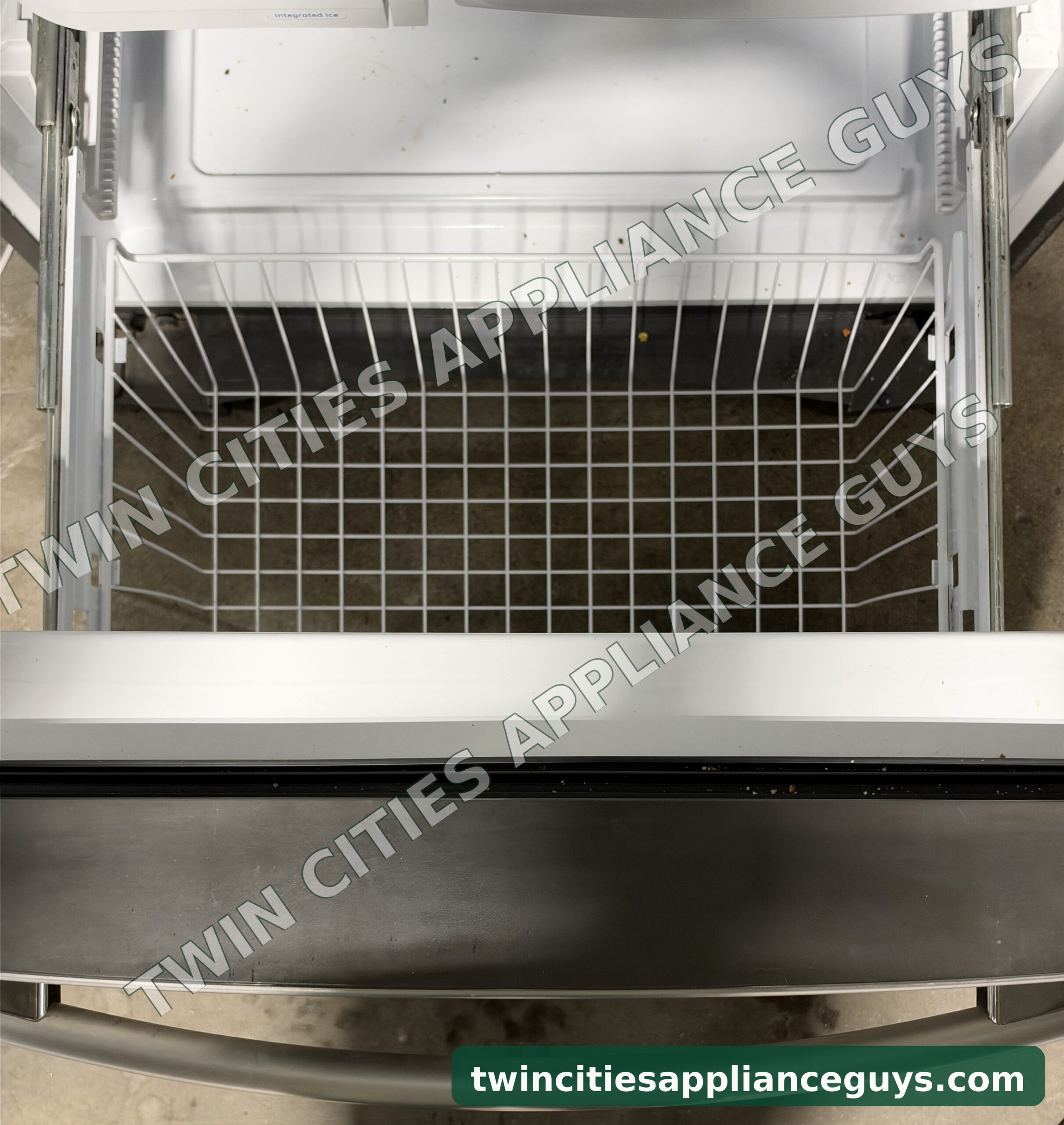 GE bottom-freezer refrigerator with the freezer drawer open showing the wire basket