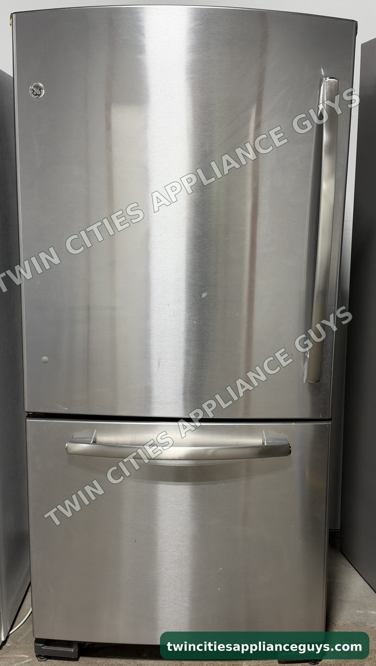 Stainless GE bottom-freezer refrigerator front view with the refrigerator door and freezer drawer closed