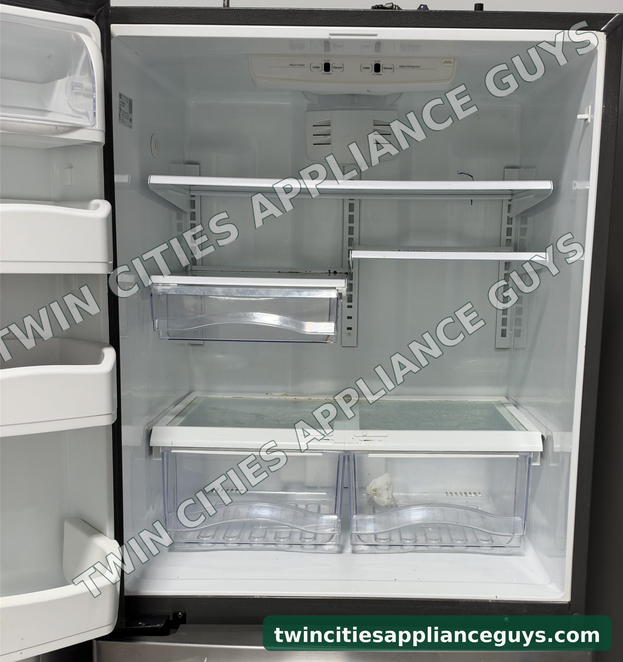 GE bottom-freezer refrigerator with the door open showing glass shelves and crisper drawers