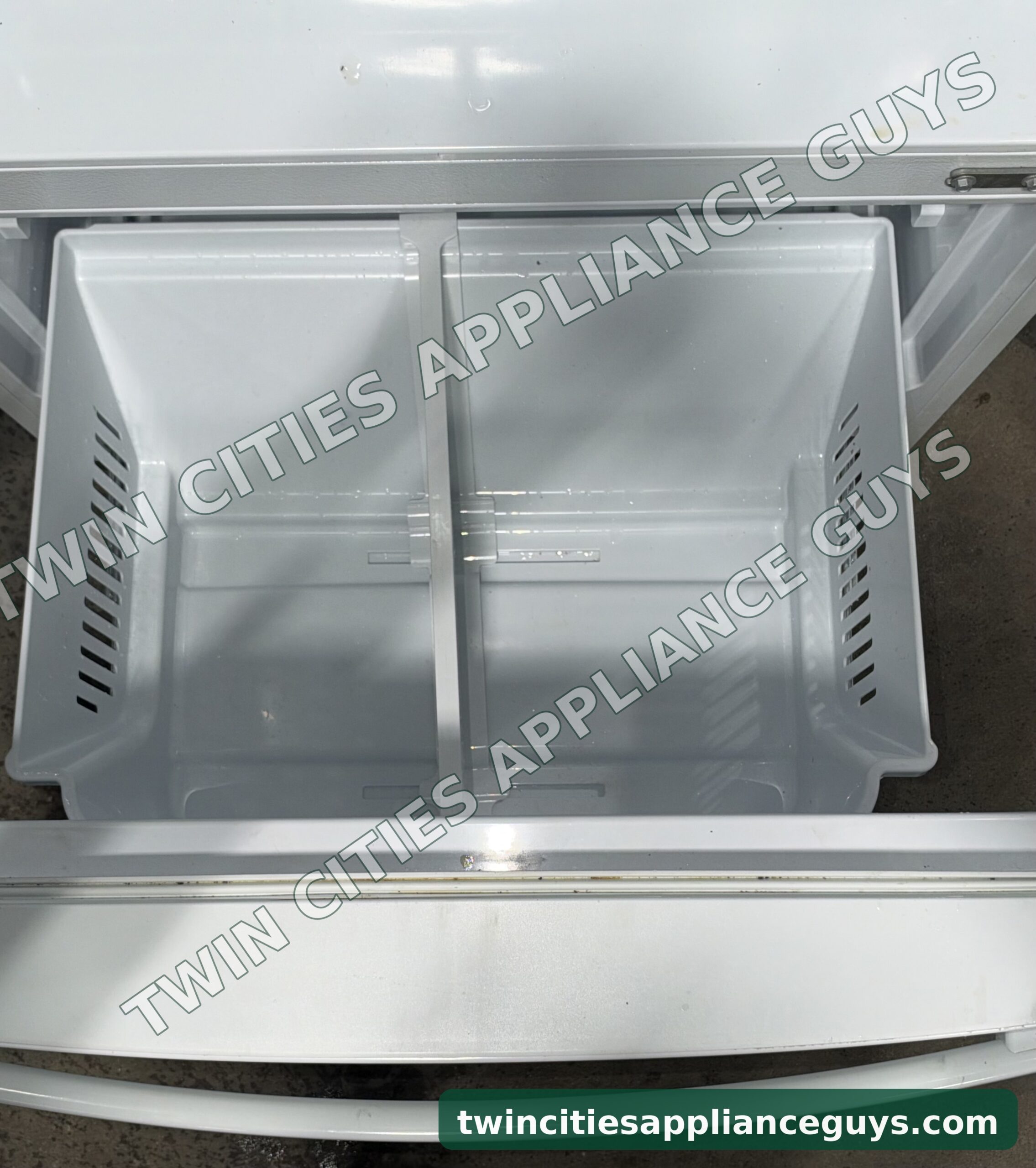 GE refrigerator bottom freezer drawer pulled open showing the empty divided freezer basket