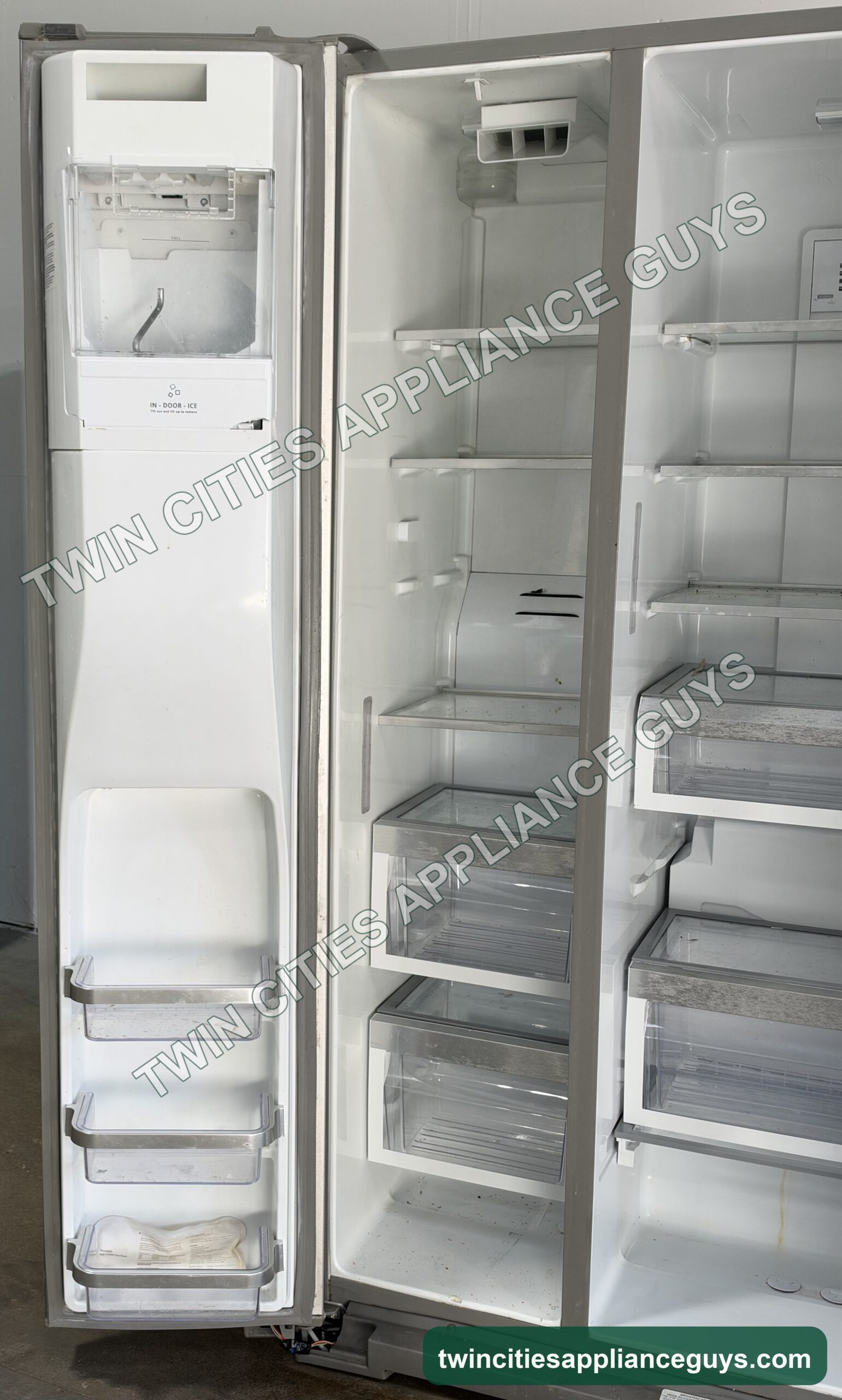 KitchenAid side-by-side refrigerator with the freezer door open showing the in-door ice compartment and bins