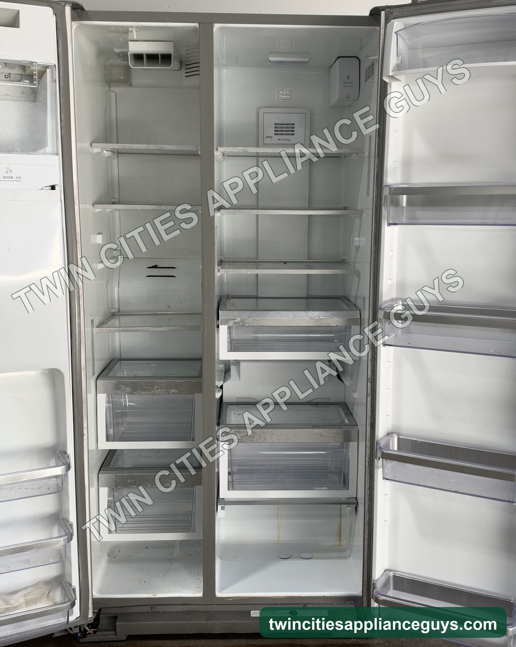 KitchenAid side-by-side refrigerator with both doors open showing shelves, crisper drawers and door bins