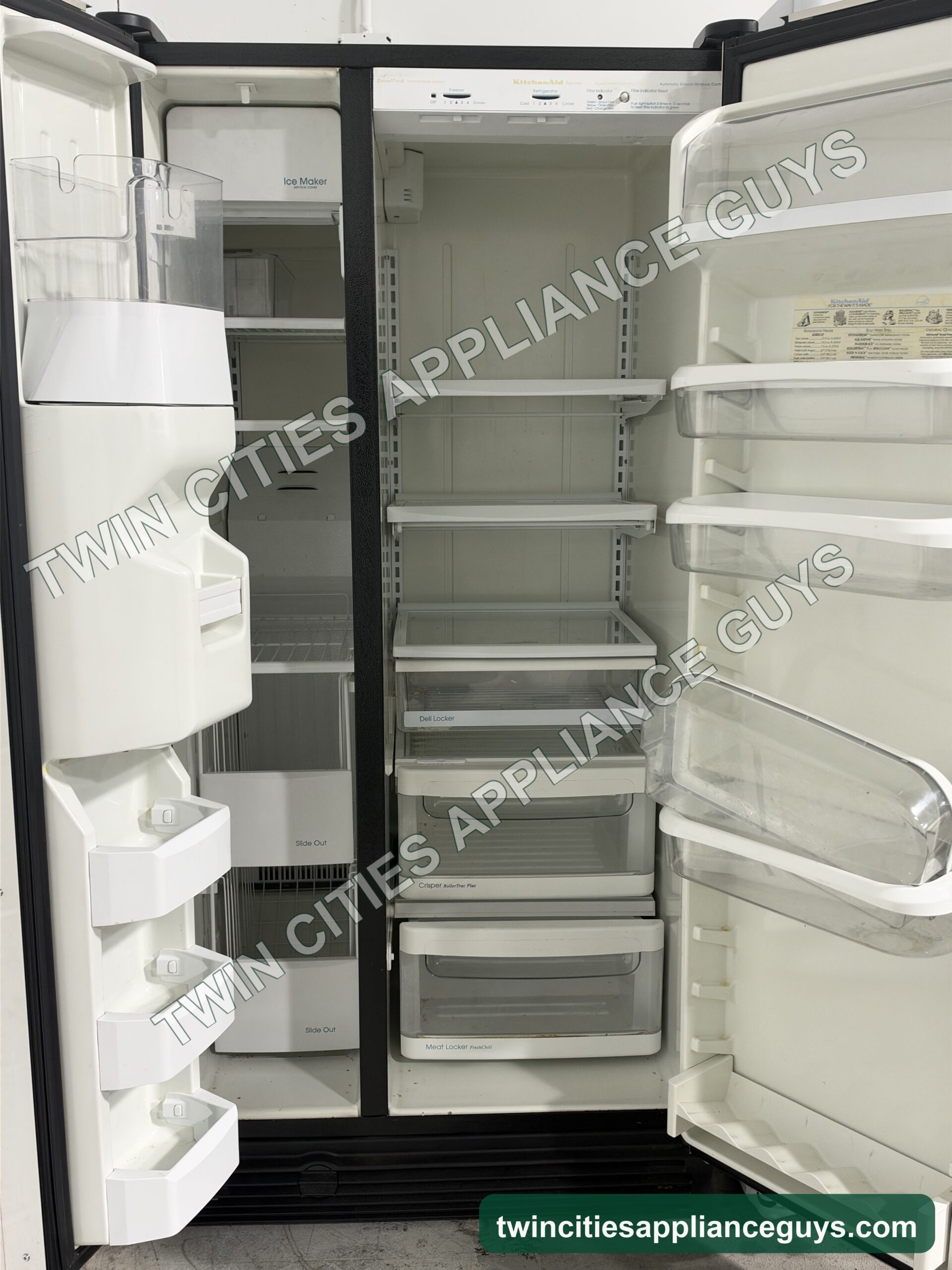KitchenAid side-by-side refrigerator with both doors open showing shelves, crisper drawers and door bins