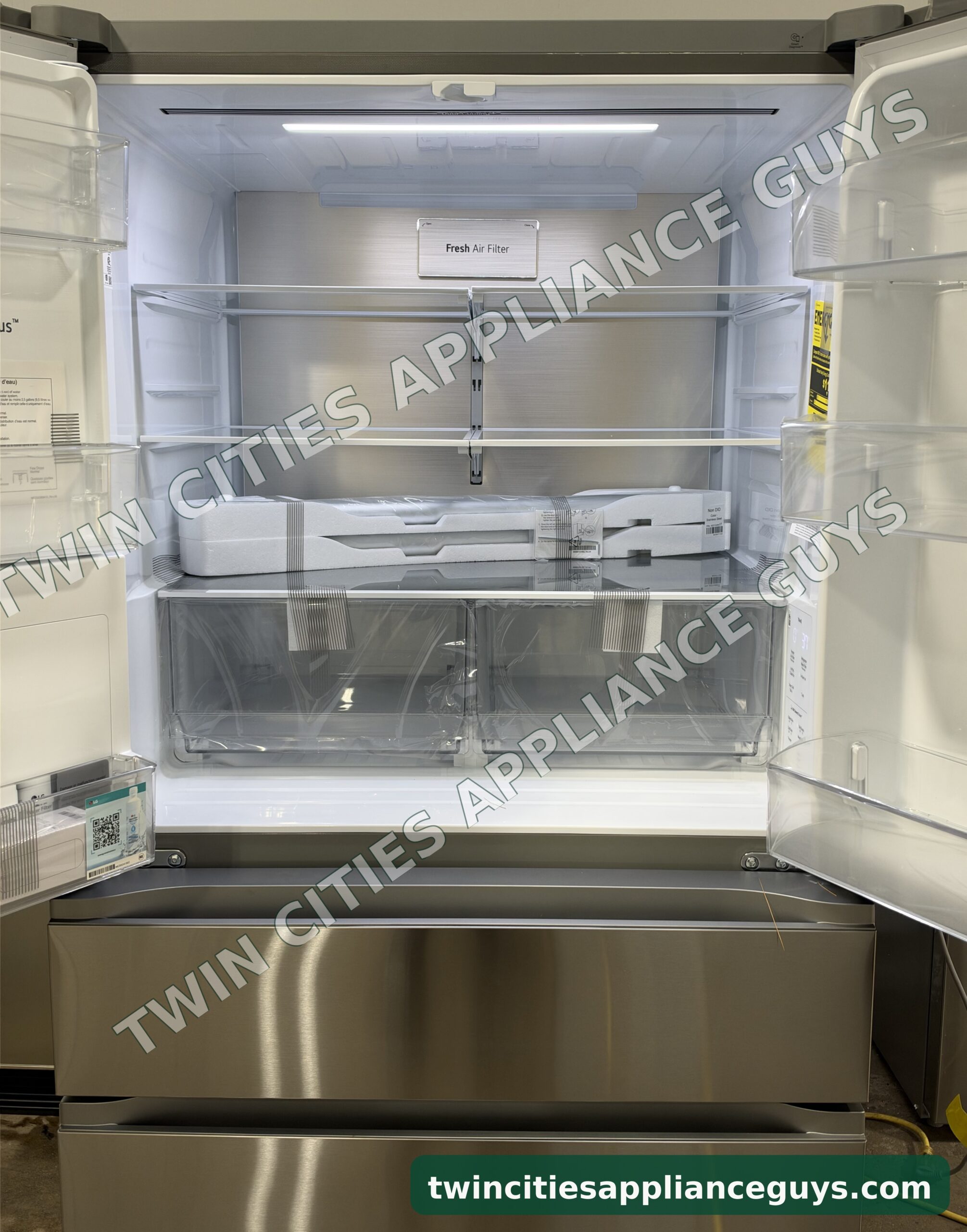 LG French door refrigerator with both doors open showing glass shelves and crisper drawers