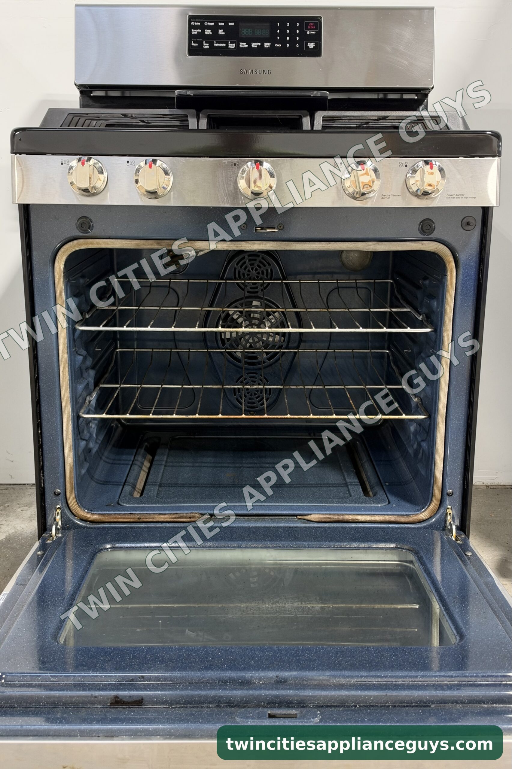 Samsung gas range with the oven door open showing two racks and the convection fan