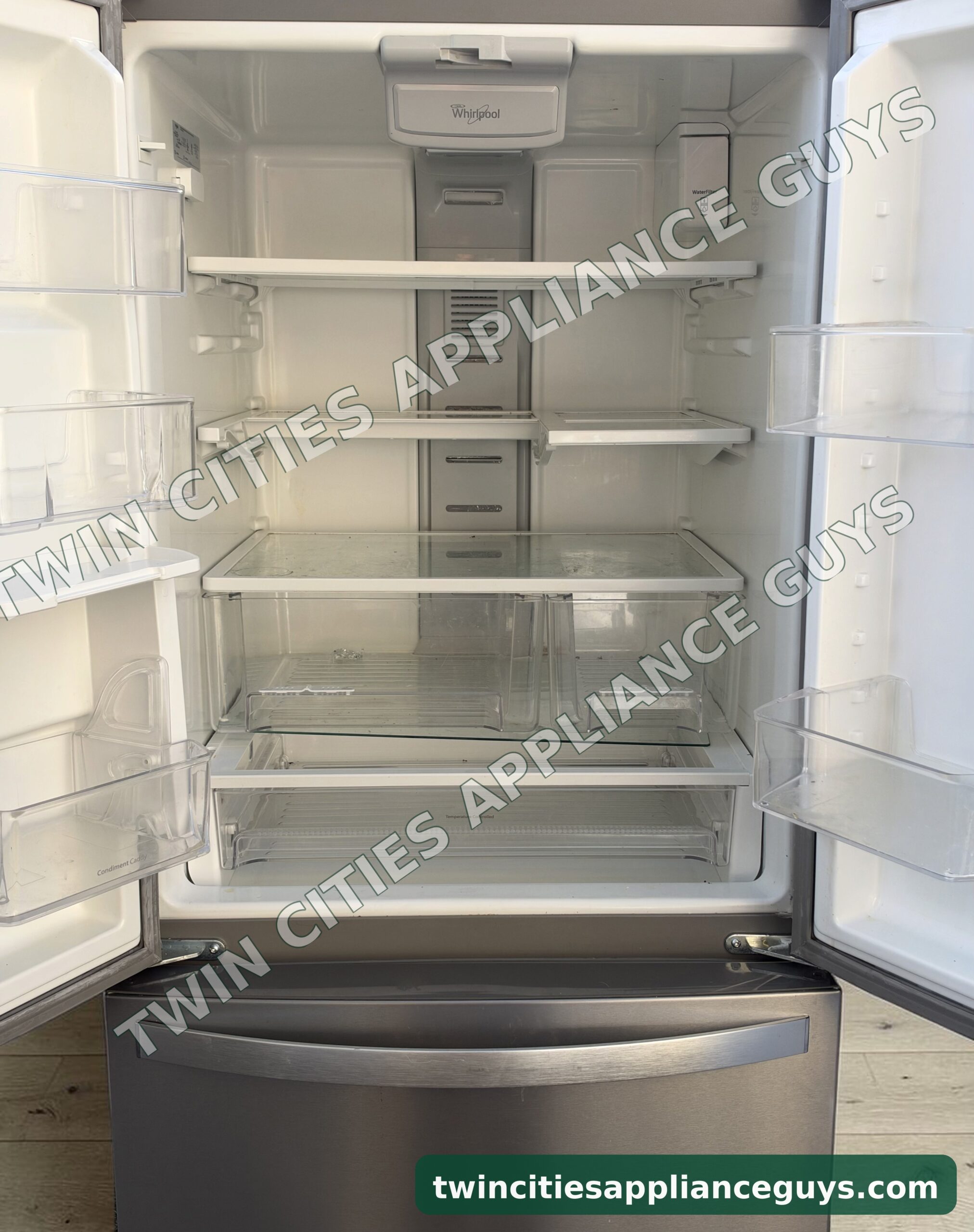 Whirlpool French door refrigerator with both doors open showing shelves and crisper drawers