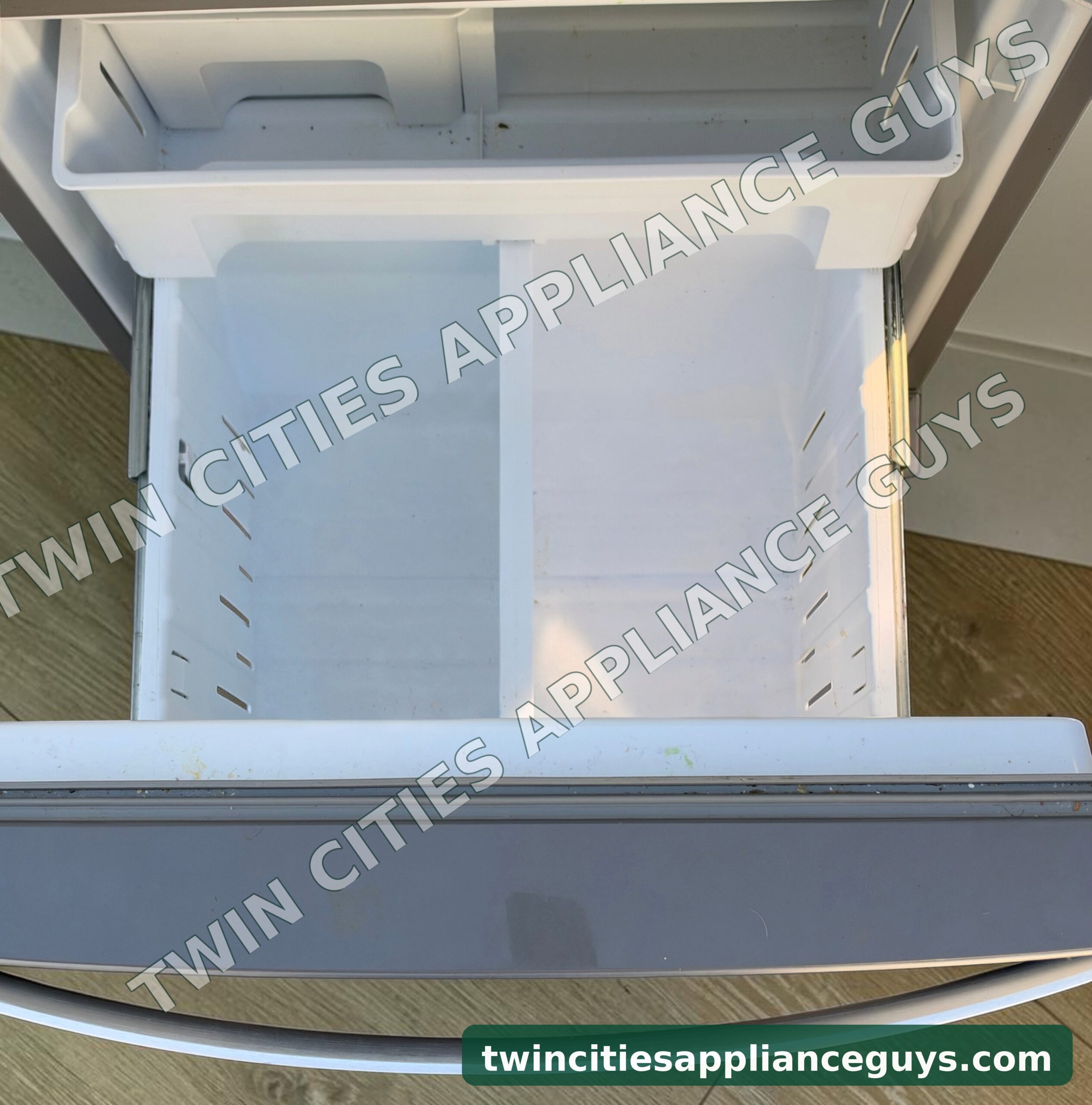 Whirlpool refrigerator bottom freezer drawer pulled open showing the empty freezer basket